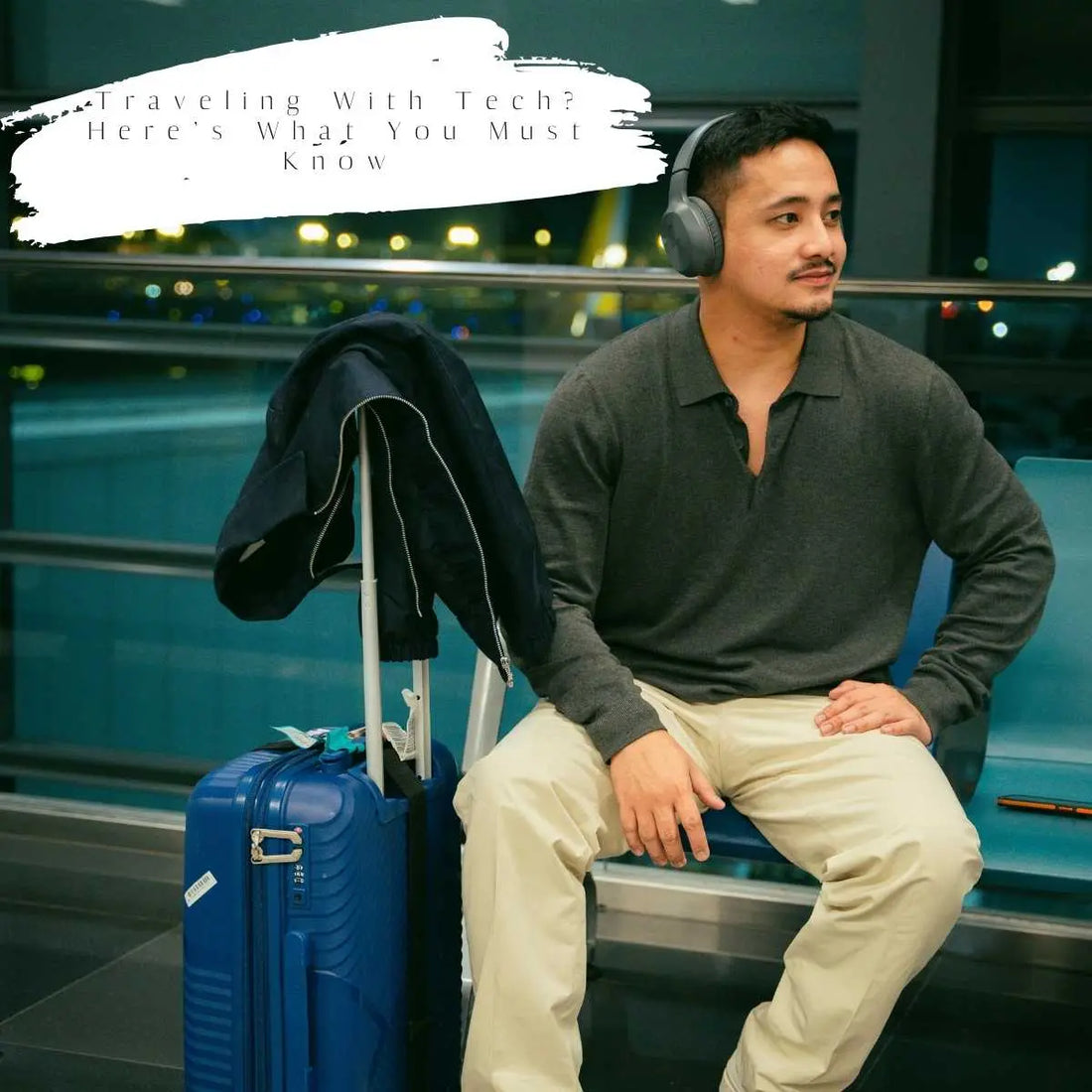 Man with wireless headphones sitting at the airport with luggage, preparing for tech-safe travel.