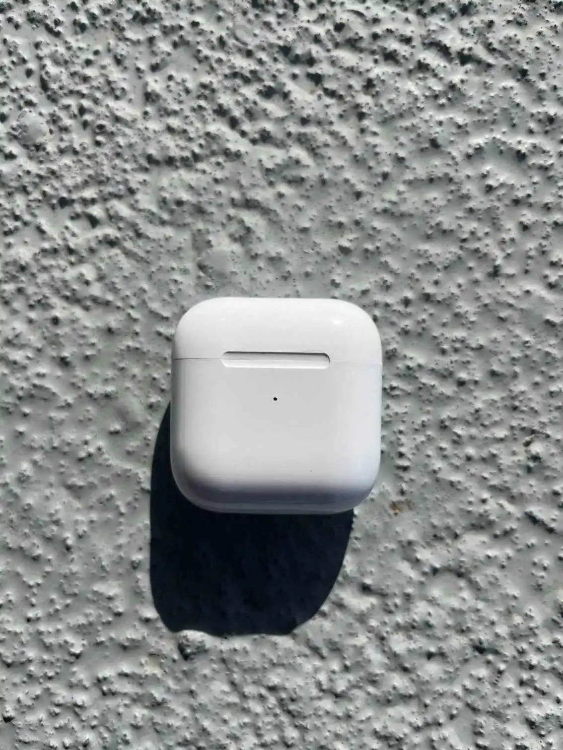 Pro 4 white earphones case closed on textured surface.