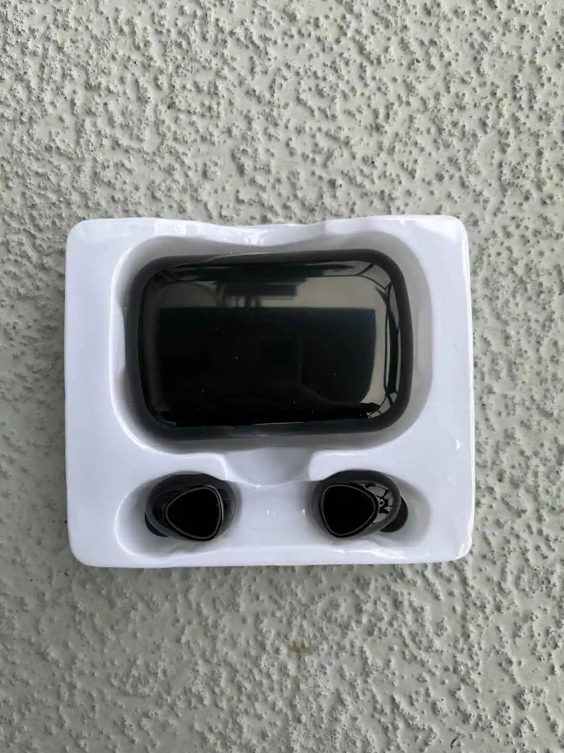 Wireless earbuds with charging case displayed in original packaging, ready for use.