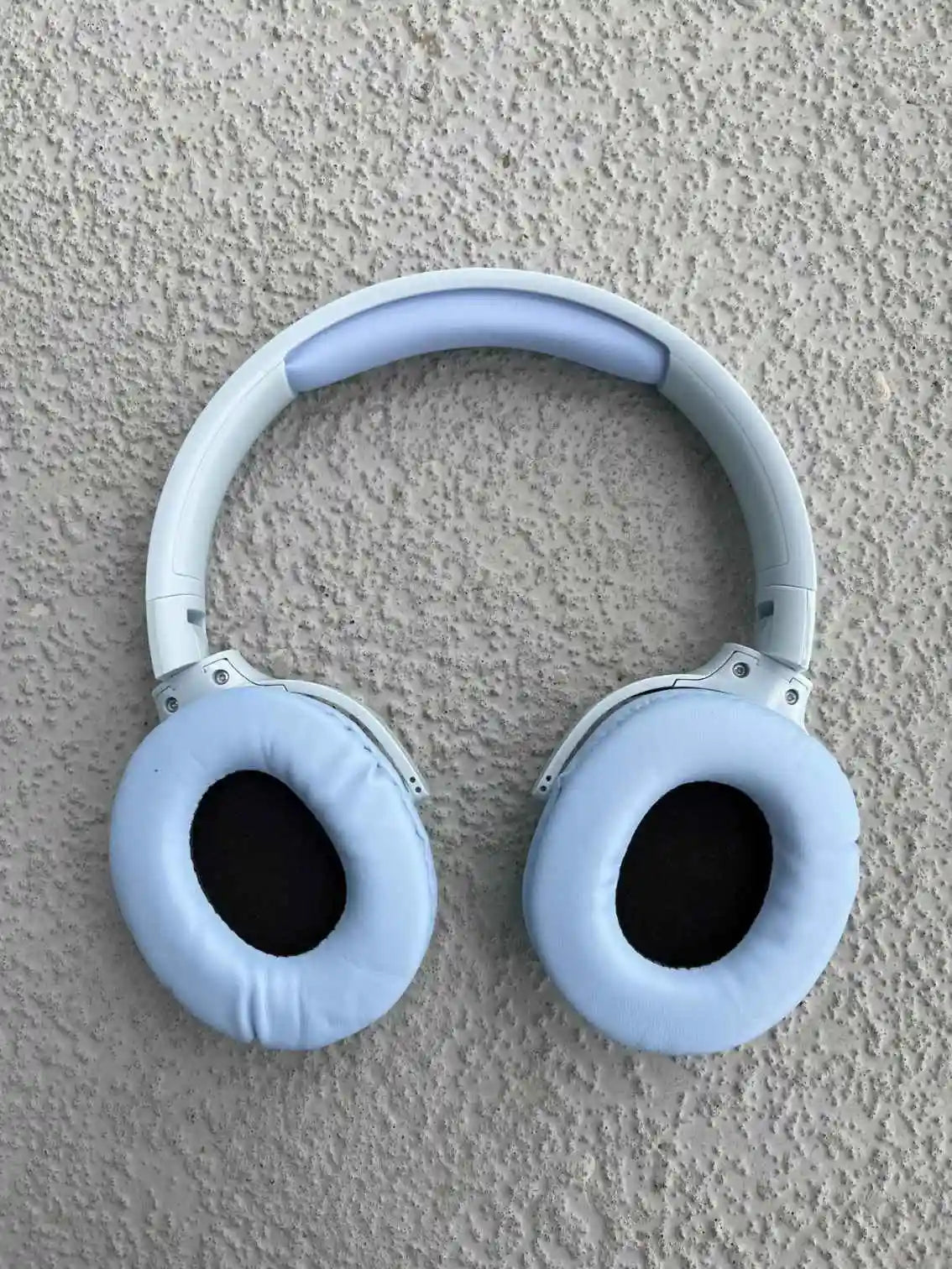 Blue wireless headphones with soft earpads and black interior.