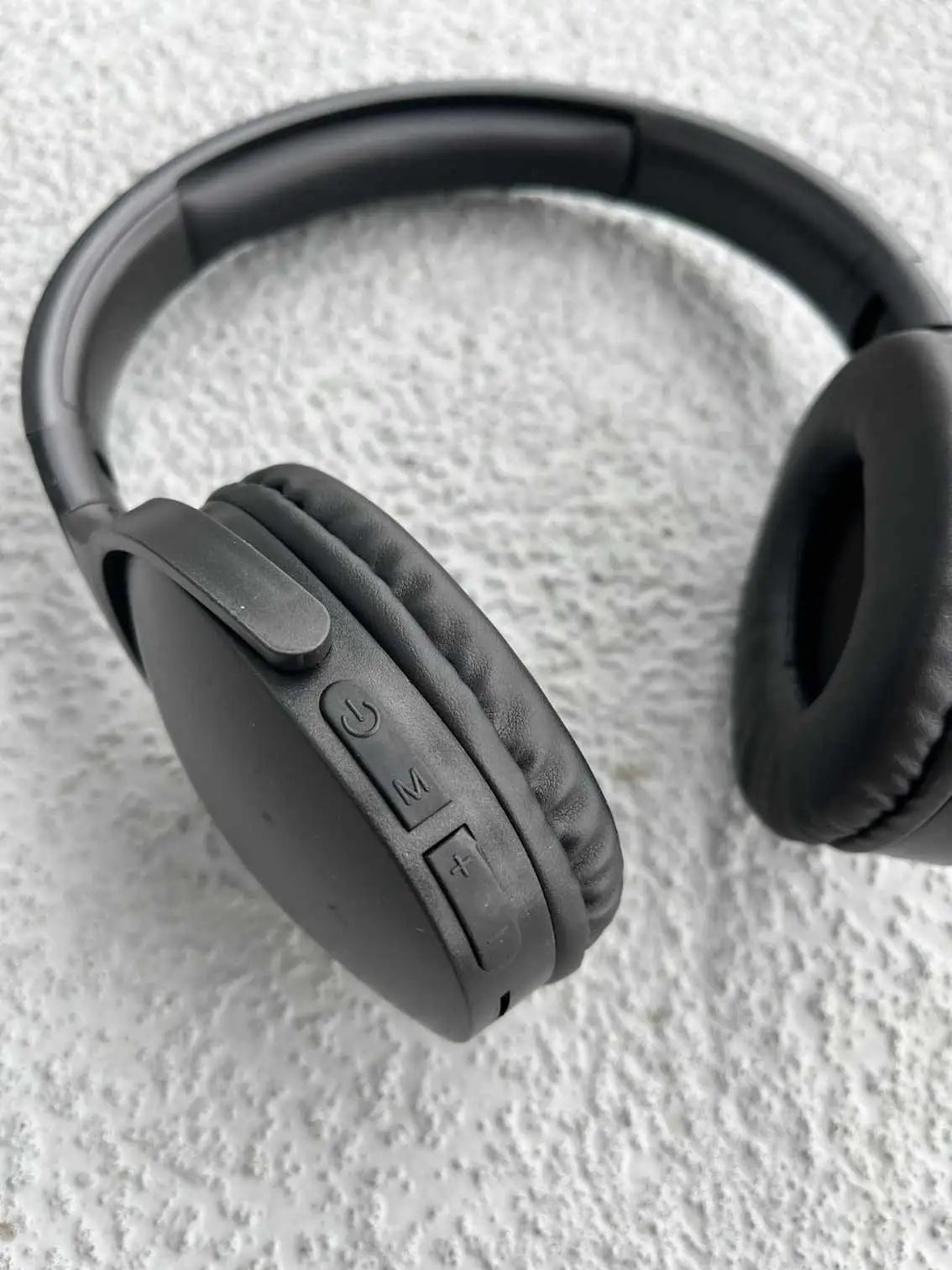 Close-up of black wireless headphones showcasing built-in controls for power, volume, and mode selection.