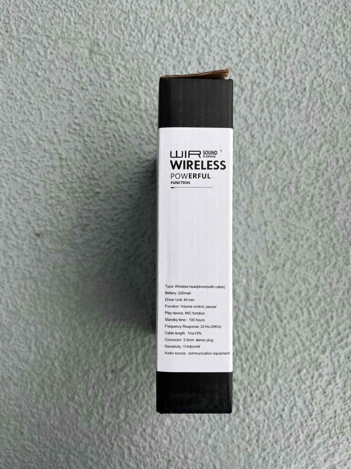 Side view of wireless Bluetooth headphones packaging, featuring product specifications and branding on a textured gray background.