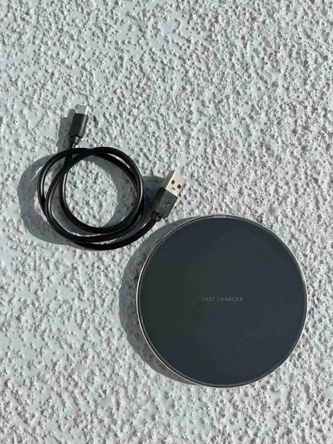 Black wireless fast charger with USB cable included, designed for efficient and convenient smartphone charging.