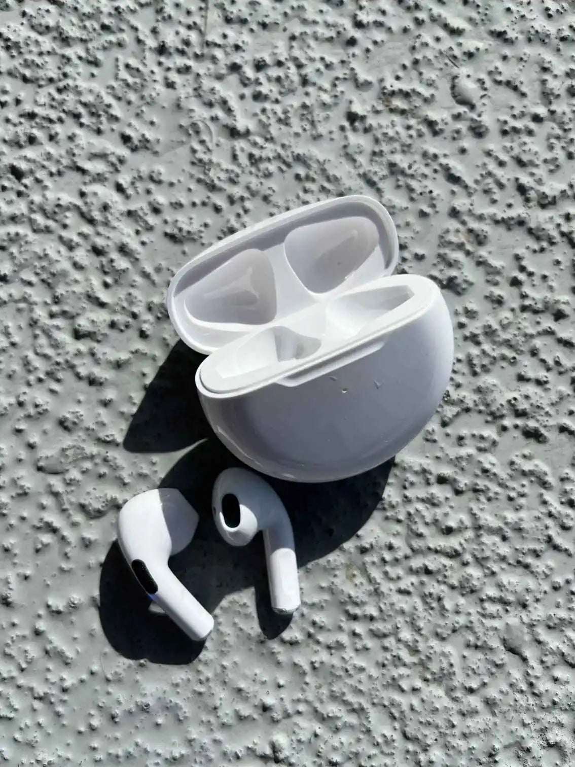 Stylish wireless earphones in white color, pulled out of the case.