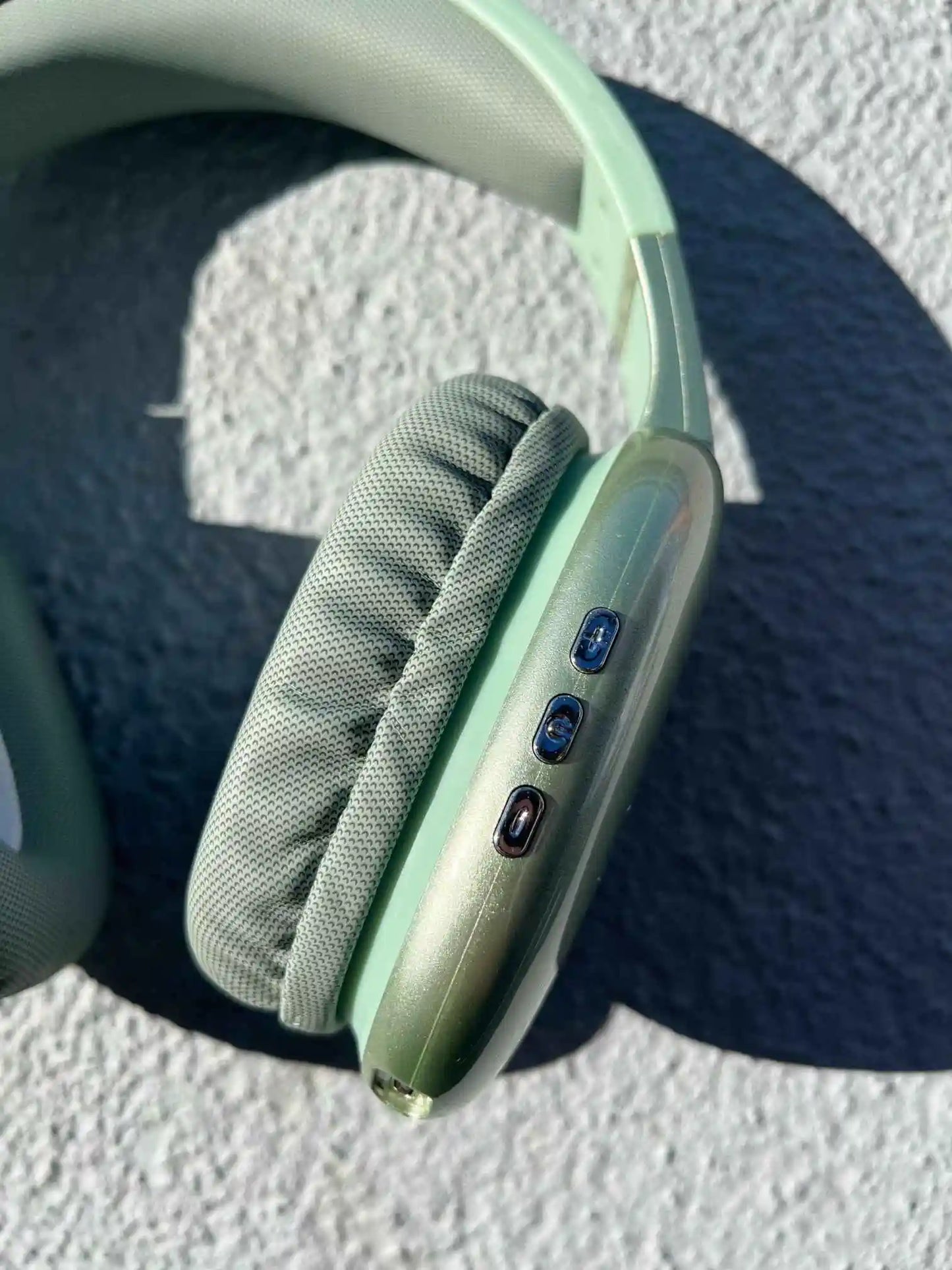 Close-up of green PG02 wireless Bluetooth headphones with control buttons and soft ear cushions.