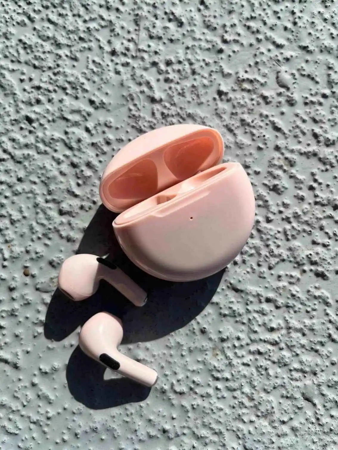 Stylish wireless earphones in pink color, pulled out of the case.