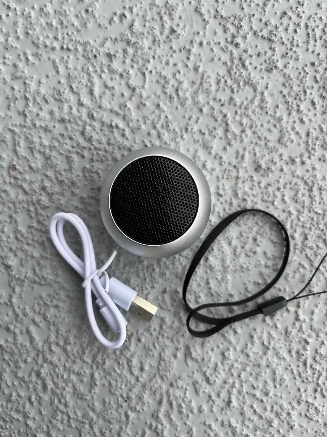 Mini silver Bluetooth speaker with accessories.