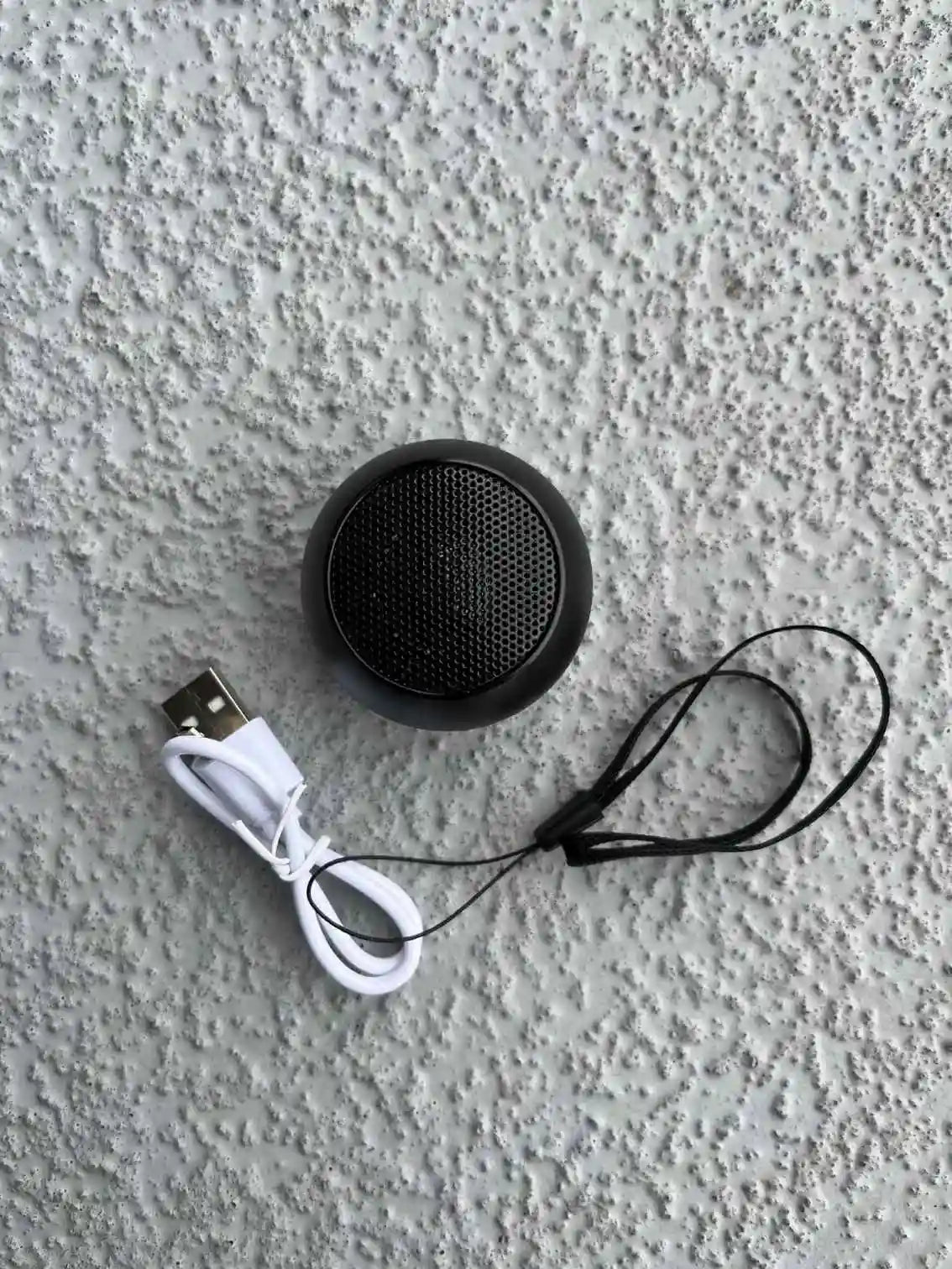 Mini Bluetooth speaker in black with accessories.