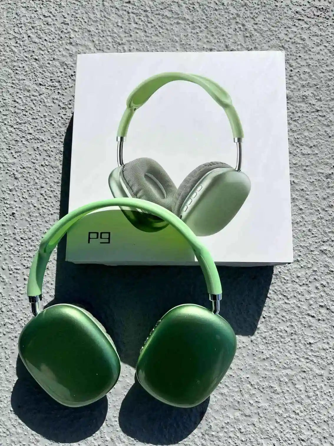 Stylish foldable wireless headphones p9 in green colour, on the box.