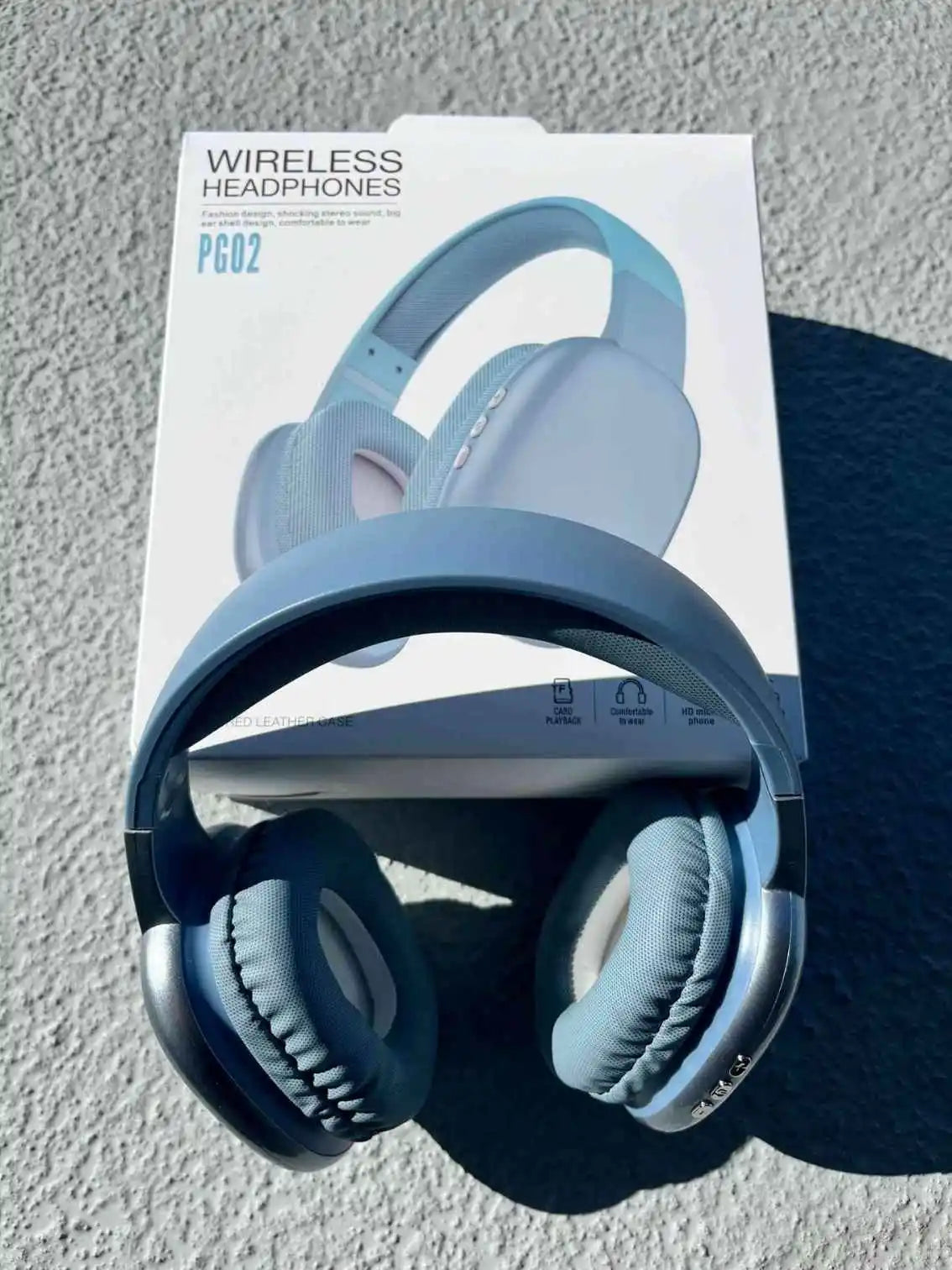 Blue wireless over-ear PG02 Bluetooth headphones are displayed in front of the product packaging with sleek design.