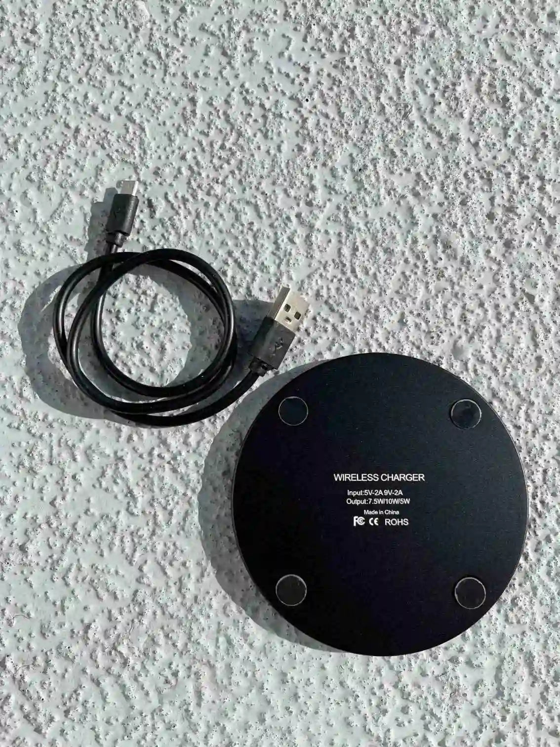 The back view of the black wireless fast charger with USB cable shows non-slip pads and technical details.