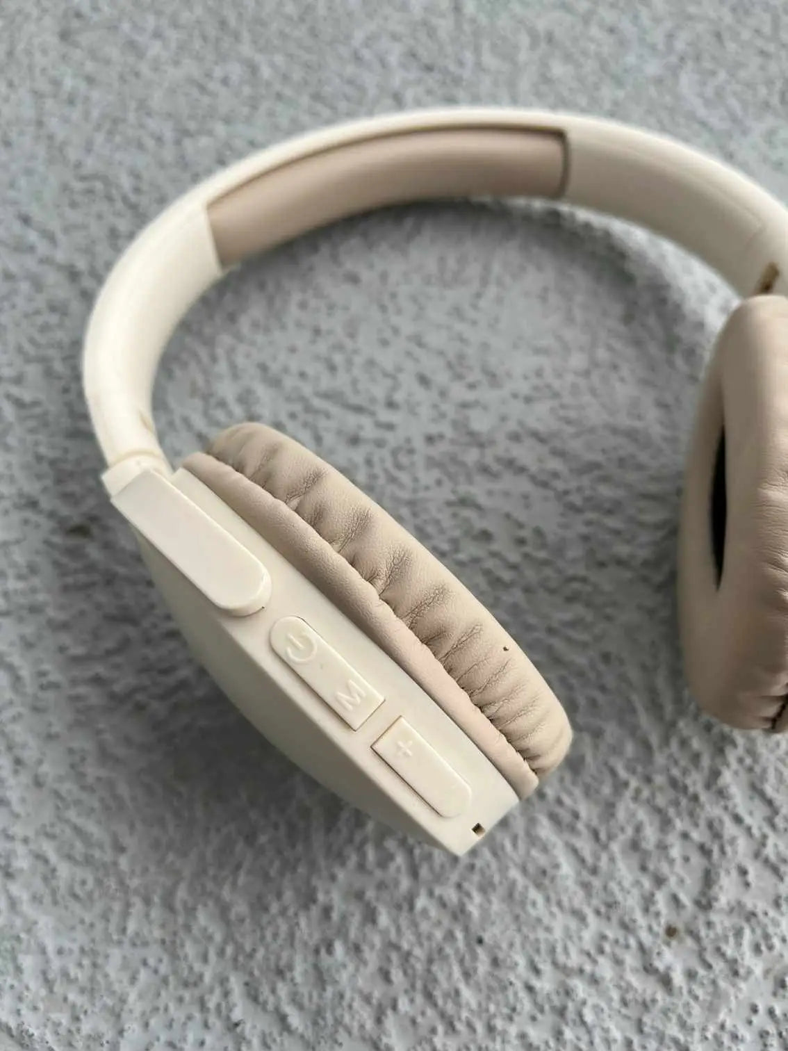 Close-up of cream wireless headphones with control buttons.