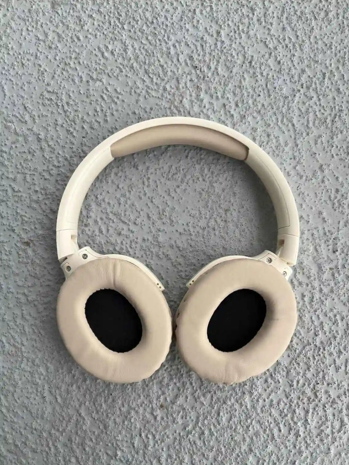 Cream wireless headphones with soft ear pads and black interior.