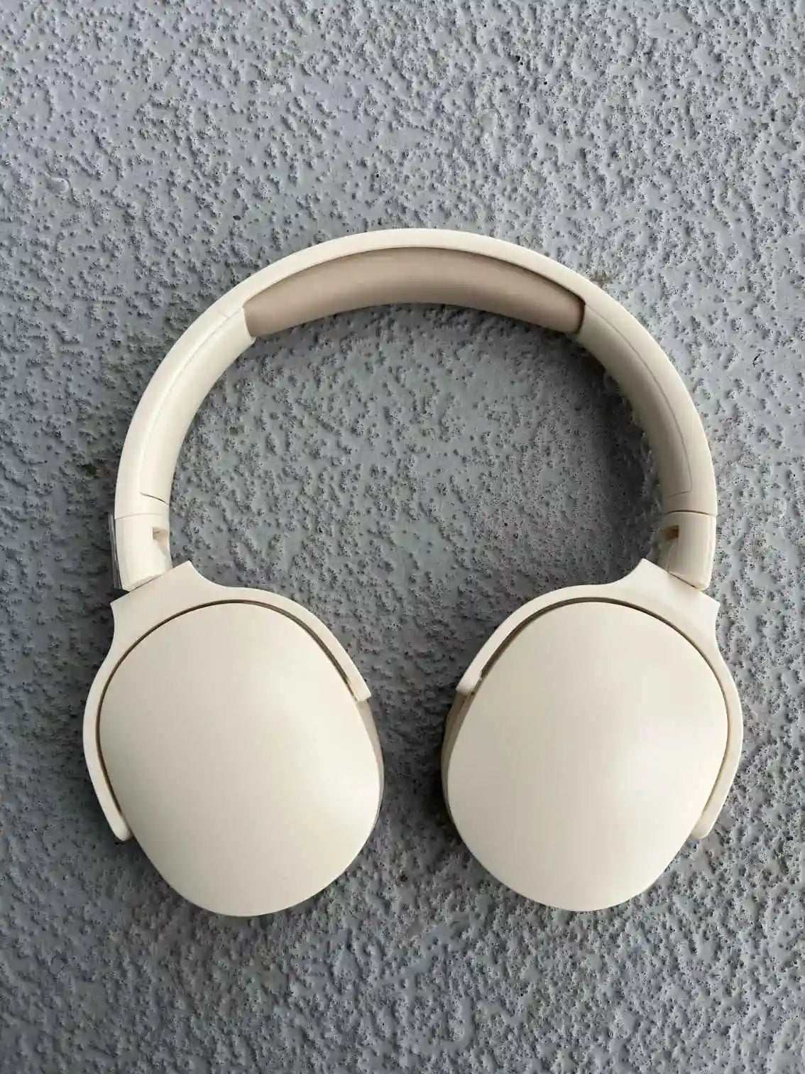 Folded cream wireless headphones top view.