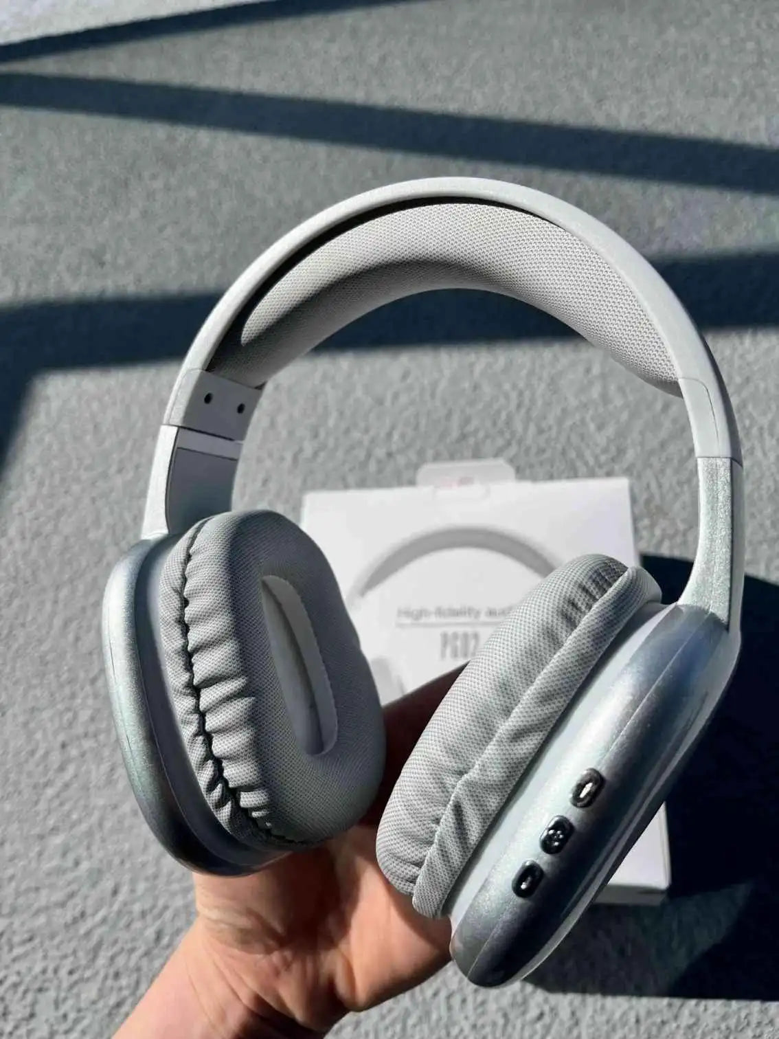 Wireless headphones PG02 in silver colour held in hand.